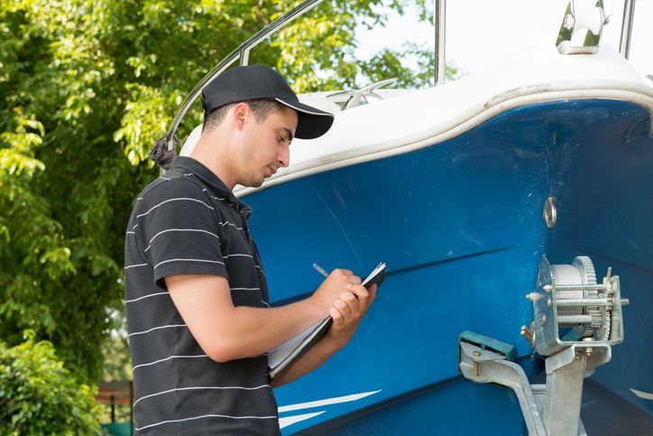 Person inspecting a boat and making notes