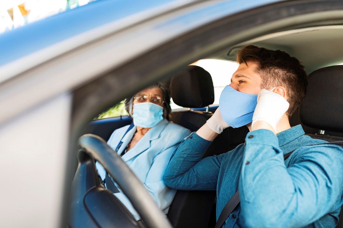 Senior woman in a car with caregiver driving
