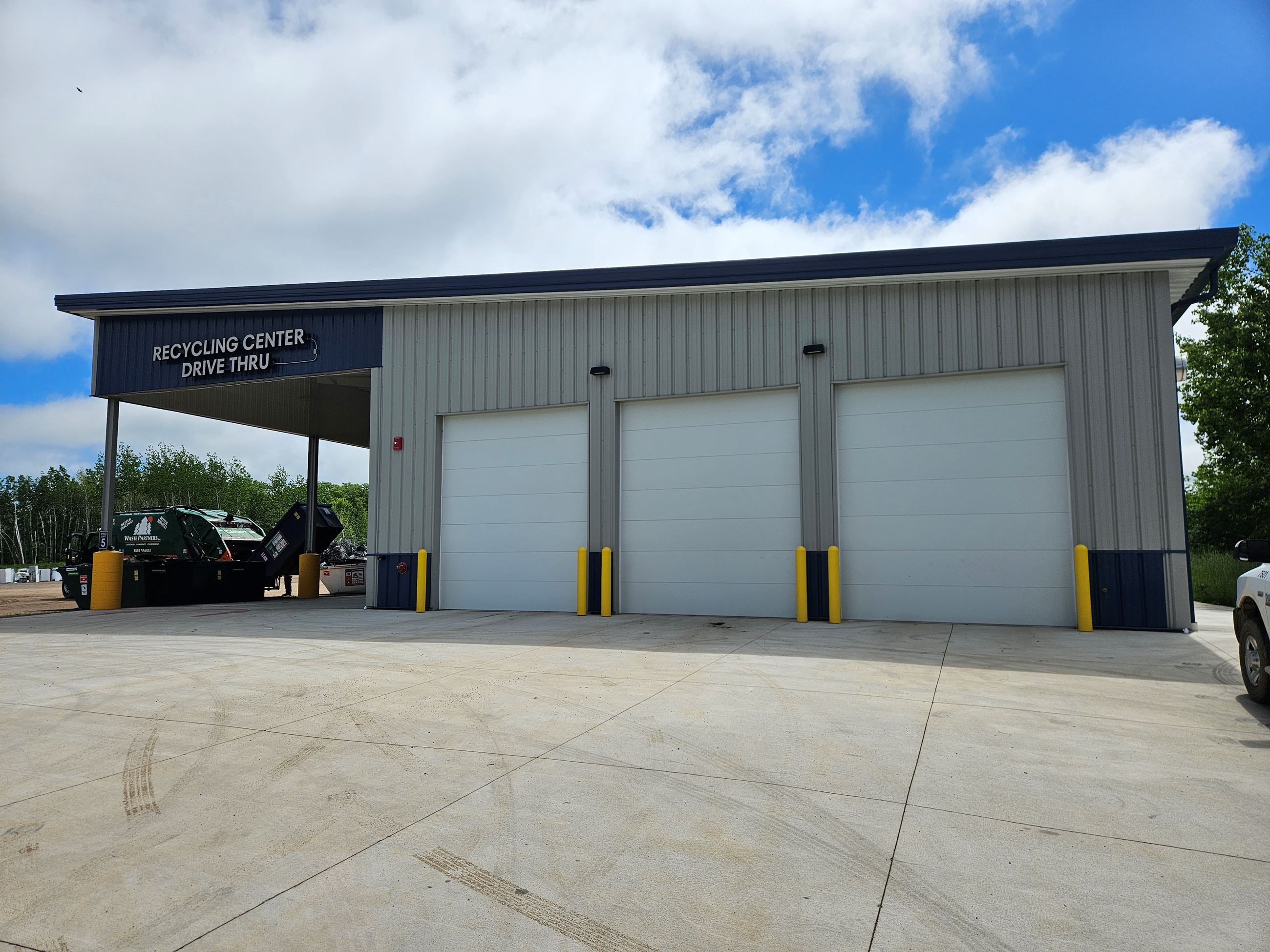 A Large Grey Building with Two large Garage Doors and an Overhang